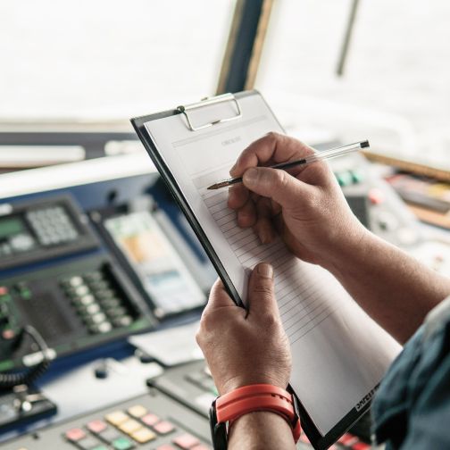 Ein Mann schreibt auf einem Klemmbrett, während er an einem Schreibtisch sitzt