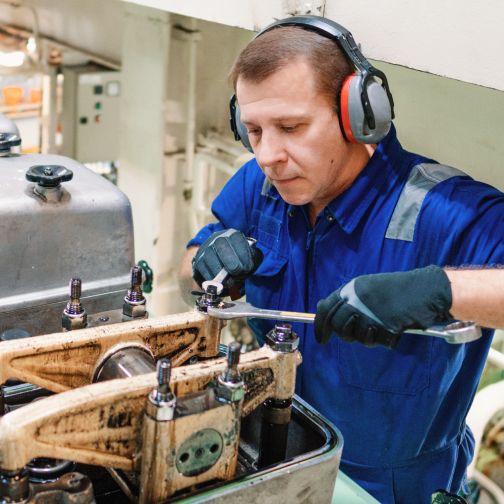 Ein Mann mit blauem Hemd und Kopfhörern arbeitet an einer Maschine